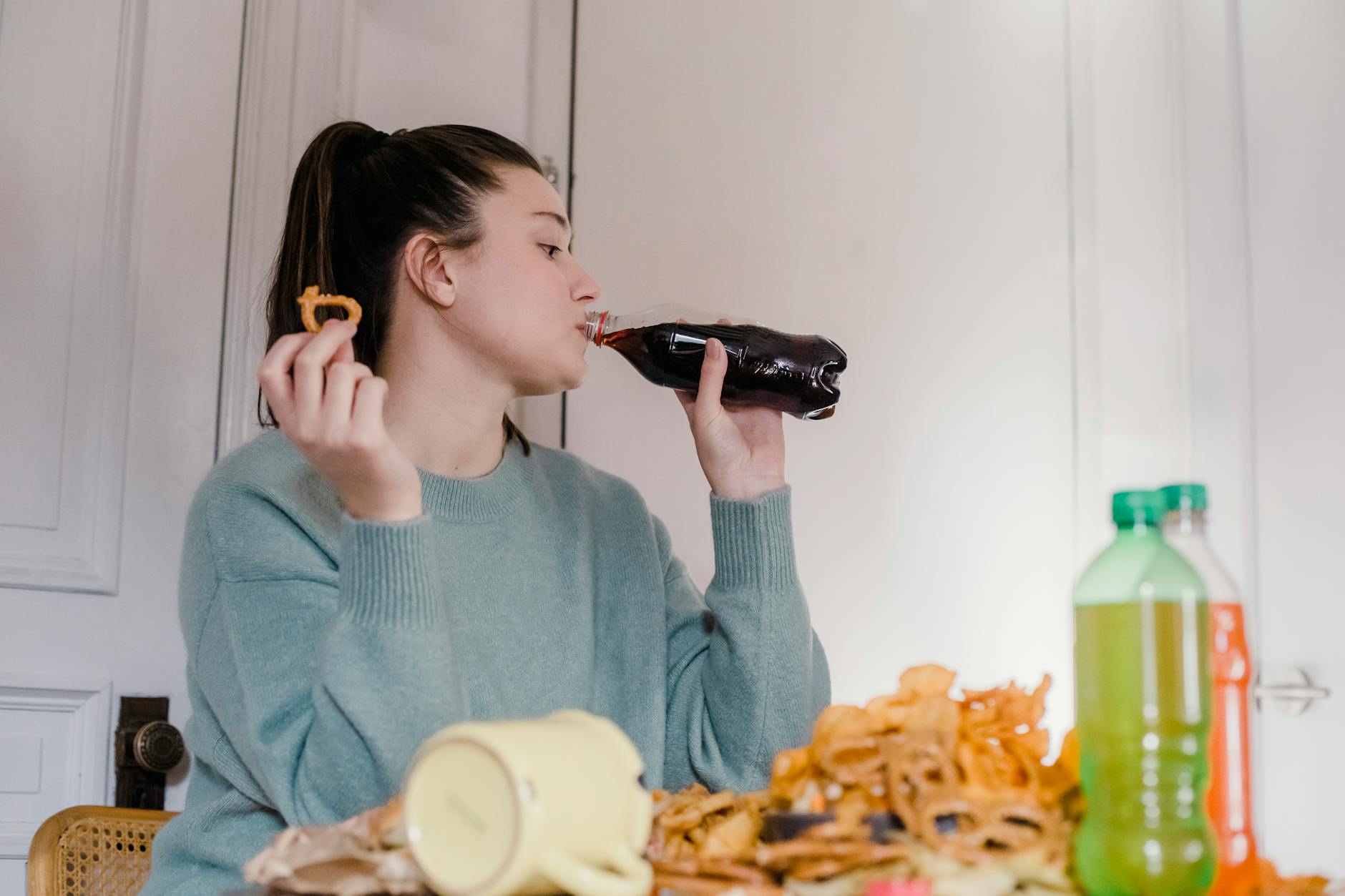 woman drinking fresh lemonade at table with junk food